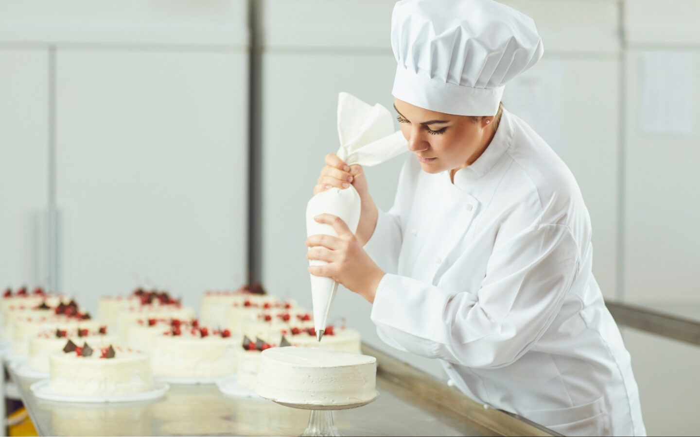 ragazza guarnisce torte in laboratorio pasticceria